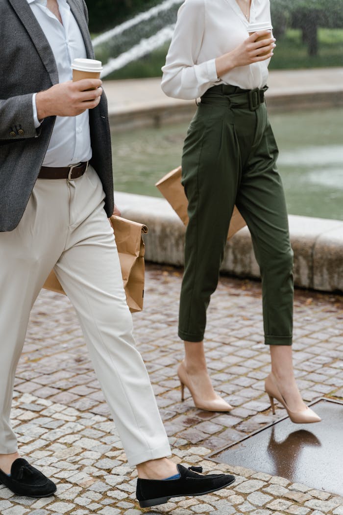 Two professionals walking outdoors holding coffee cups and paper bags